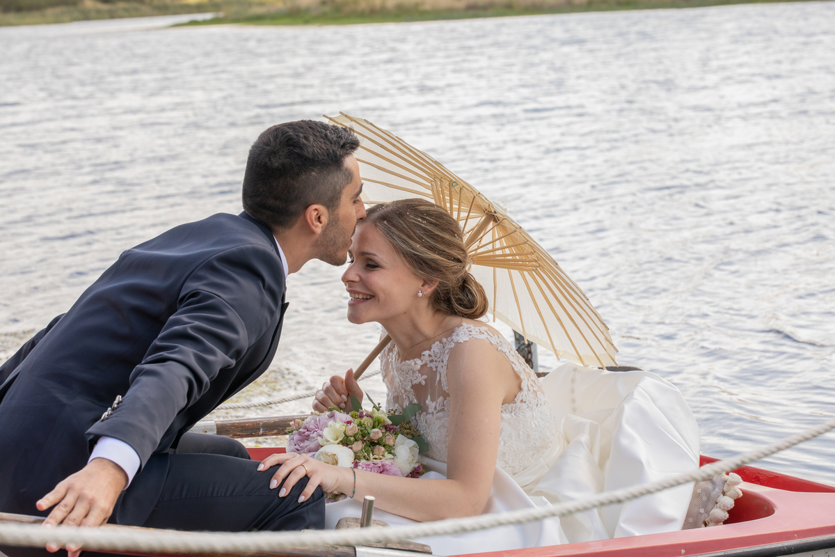 Noivo beija noiva na testa no interior do barco 