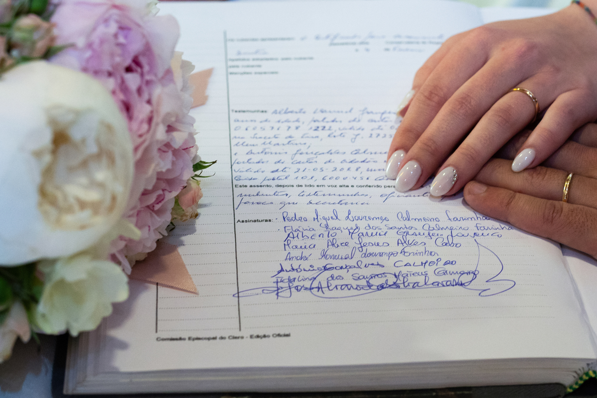 Livro de assinaturas com mãos dos noivos e sob o mesmo