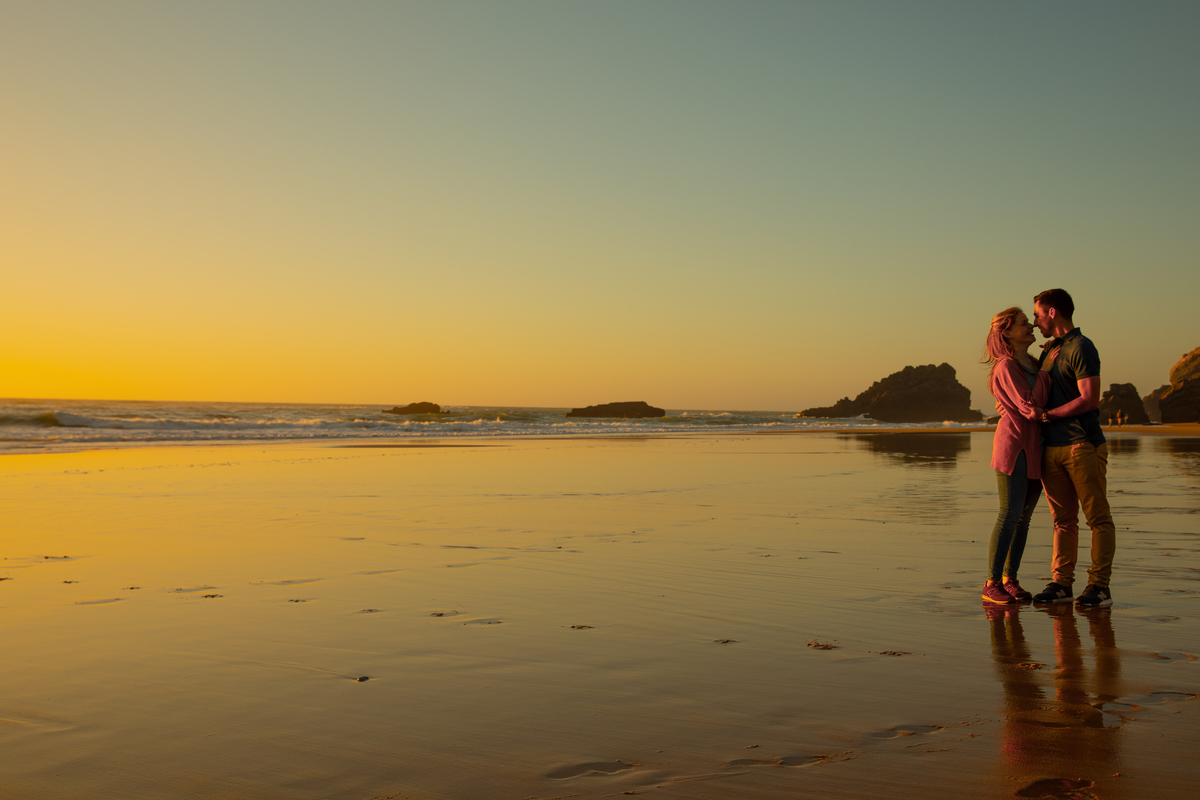 Flávia e Pedro abraçando-se junto ao mar