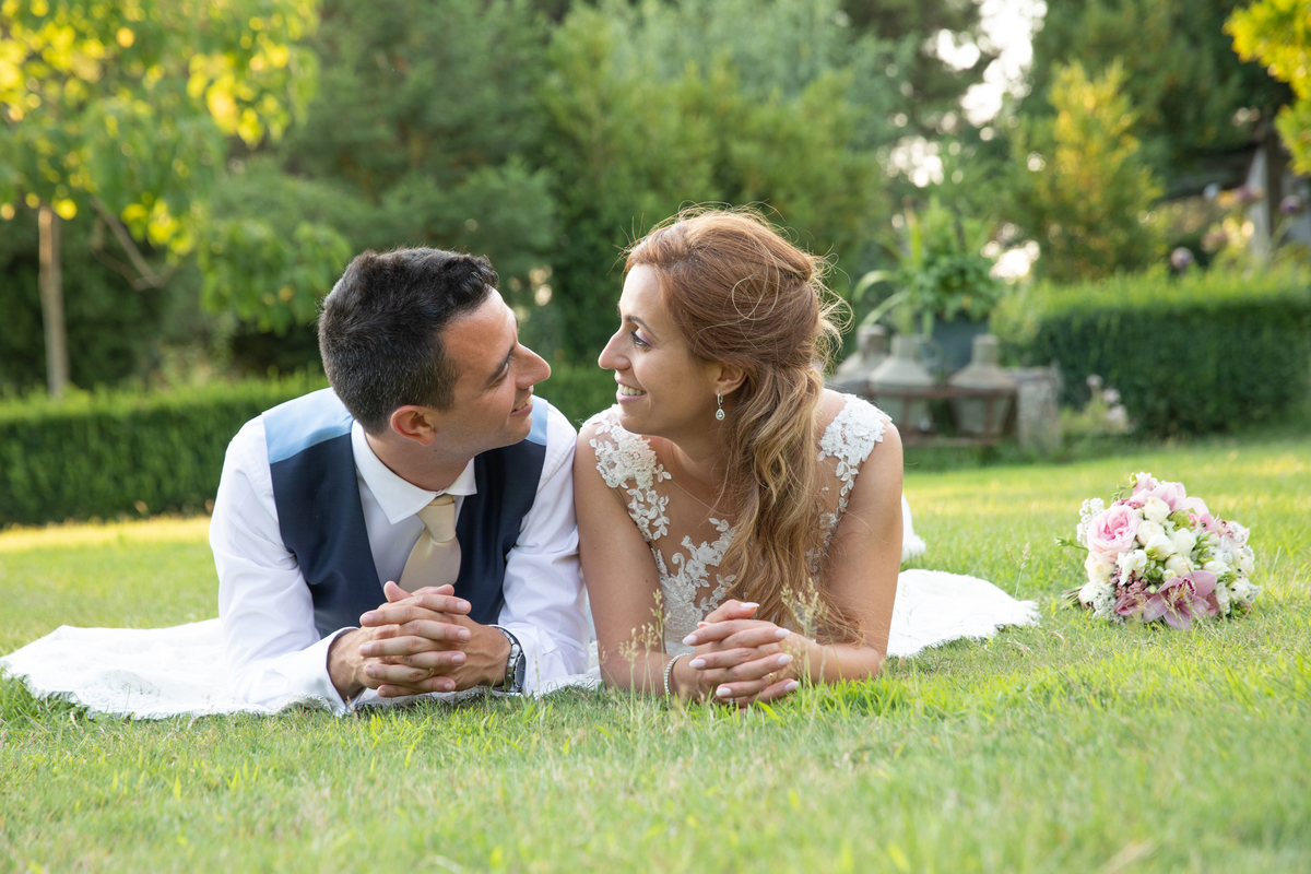 Noivos deitados no jardim lado a lado observando-se