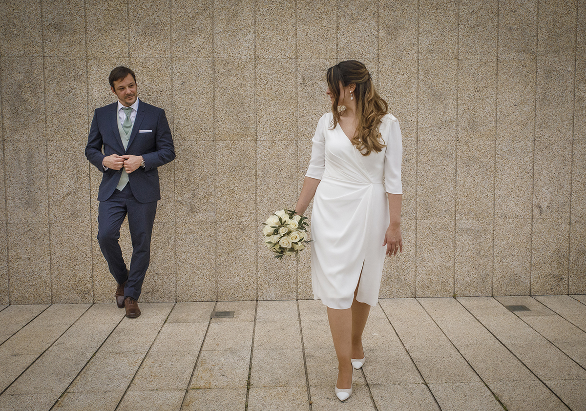 No cenário inicial, Nuno surge encostado à parede moderna de pedra, olhando para Rita ao longe. Ela, bouquet na mão, parece caminhar na direção dele, com um olhar cúmplice. Casamento Viseu