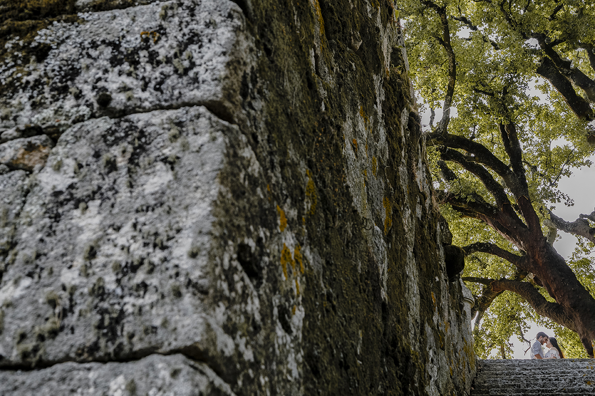 O muro antigo domina a imagem, mas são as testas unidas dos dois no topo da escada que irradiam felicidade e um afeto que transcende o tempo.