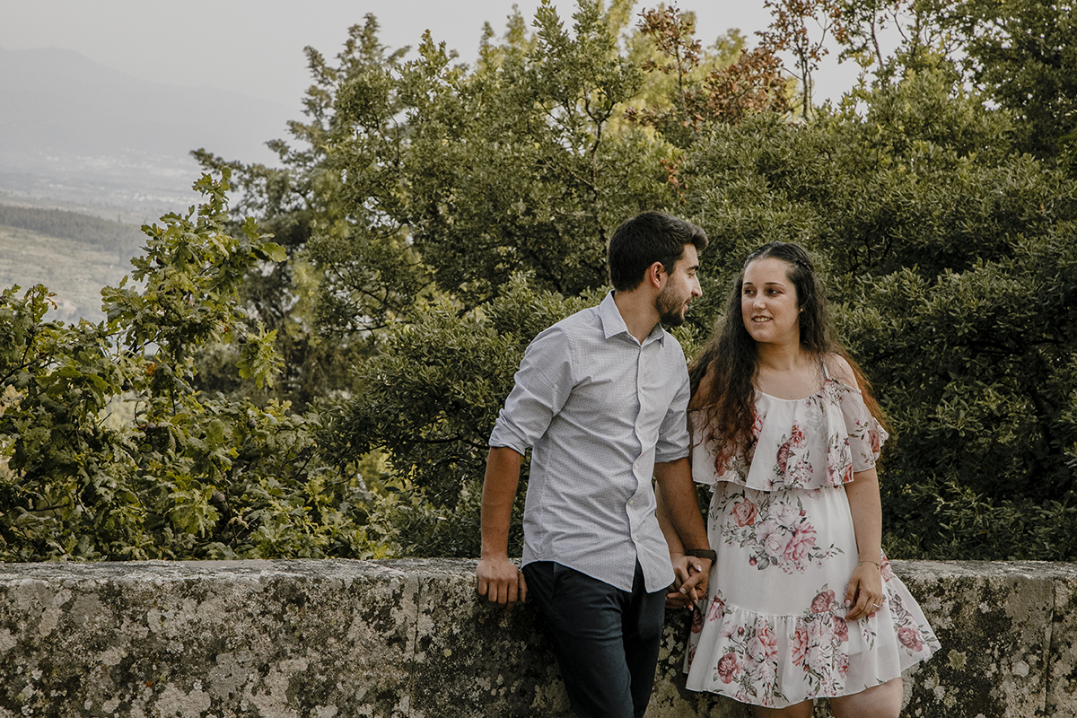 Juntos, encostados ao muro, as mãos dadas e os olhares suaves de Juliana e Miguel revelam uma serenidade apaixonada que aquece o coração.