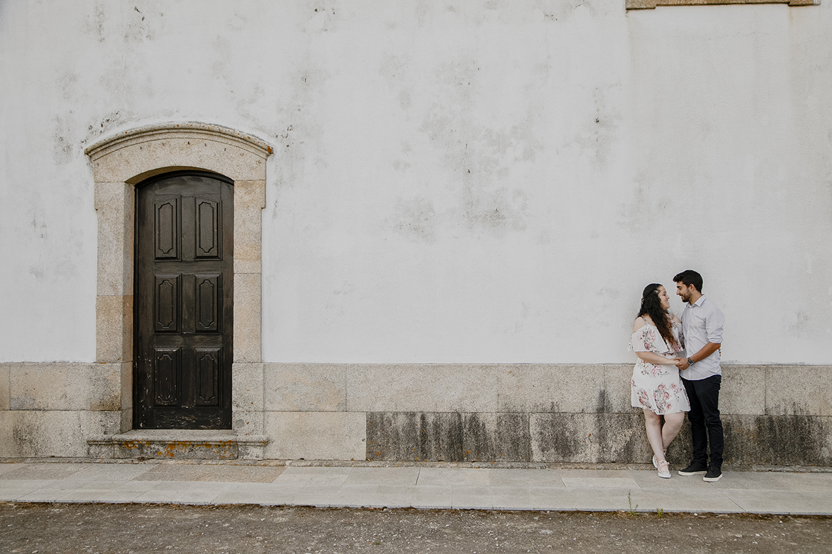 De corpo inteiro, os dois encostados à parede, mãos dadas e apaixonados, Juliana com uma perna dobrada, numa pose cheia de graça e leveza.