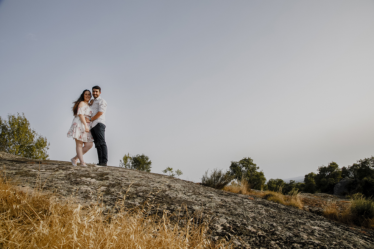 Encostados um ao outro, Miguel segura a barriga de Juliana, transmitindo cuidado e carinho em cada gesto.