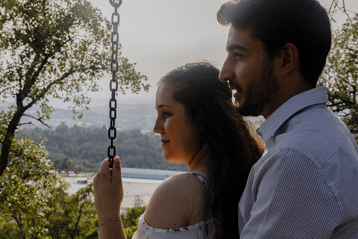 De costas ligeiramente viradas para o lado, olham para o horizonte com expressões sérias mas serenas, vivendo juntos o momento presente.