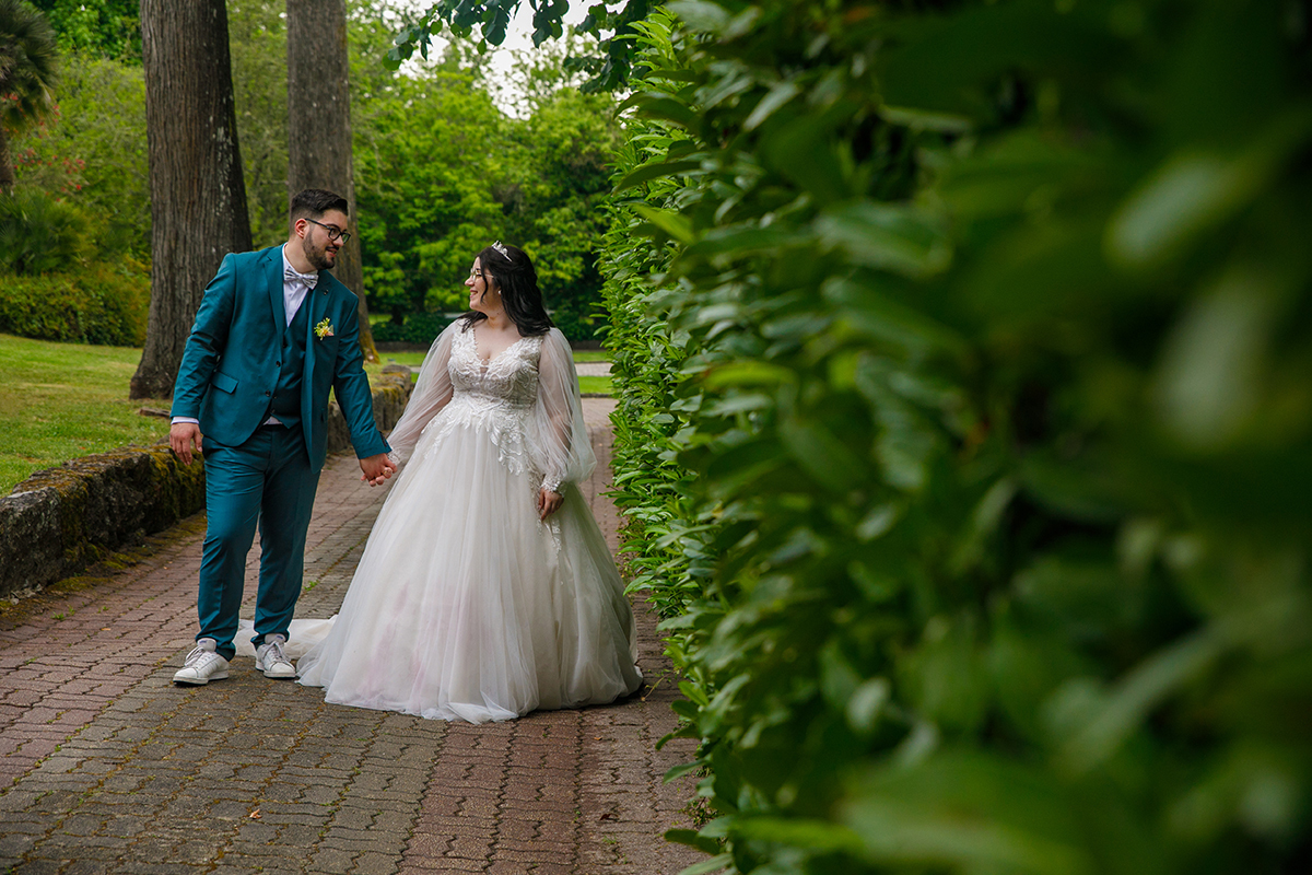 Caminham de mãos dadas pela calçada, lado a lado, os seus olhares entrelaçados repletos de felicidade e paixão, enquanto o fundo desfocado os envolve numa aura de sonho e promessa eterna.