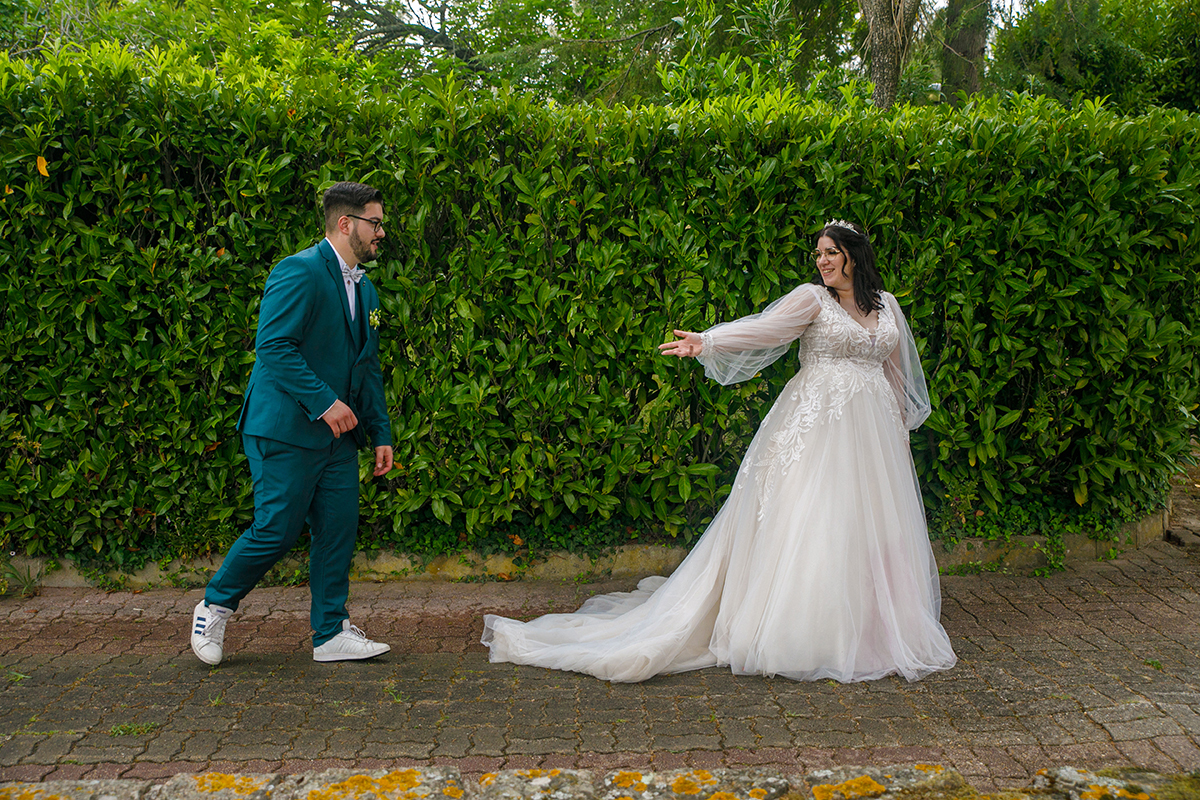 Fotografados de lado a correrem pela calçada, Carolina avança sorridente olhando para trás, estendendo a mão a Tiago que a persegue alegre, o vestido dela esvoaçando como uma dança e a natureza verdejante completando a magia do momento.
