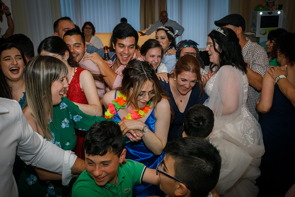 Entre a multidão animada, os convidados comprimem-se numa roda de alegria e dança, com Carolina entre eles, todos envolvidos num momento de pura diversão e comunhão que ficará na memória de todos.