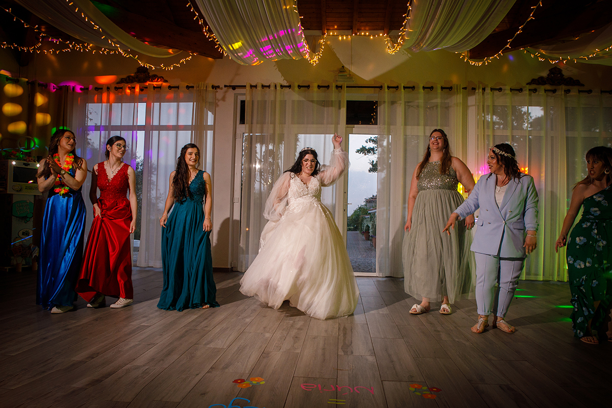 Carolina domina o centro da pista com uma dança cheia de poder e felicidade, as amigas sorriem e acompanham-na animadamente, enquanto outras olham divertidas, capturando a essência de um momento vibrante e alegre.