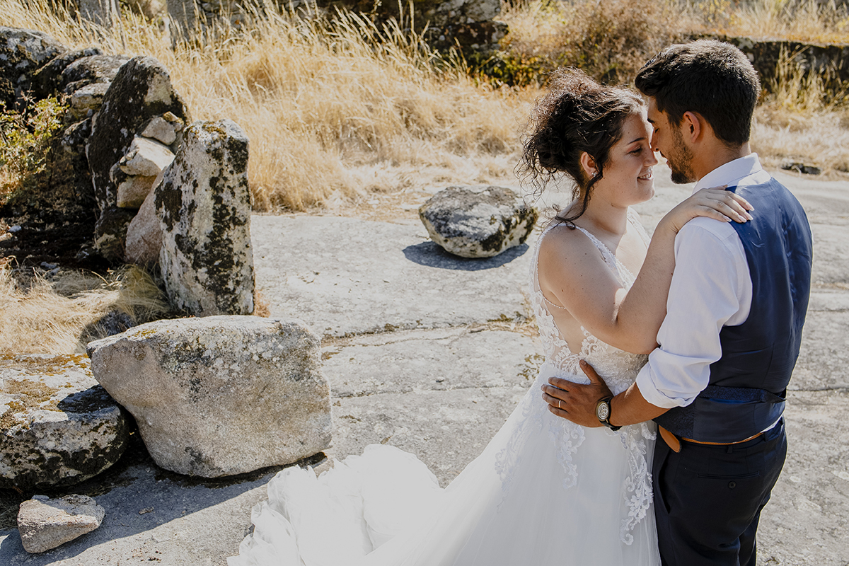 Num plano dos joelhos para cima, Juliana coloca as mãos nos ombros de Miguel, que a segura pela cintura. Com os olhos fechados, encostam os narizes, sorrindo em sintonia.