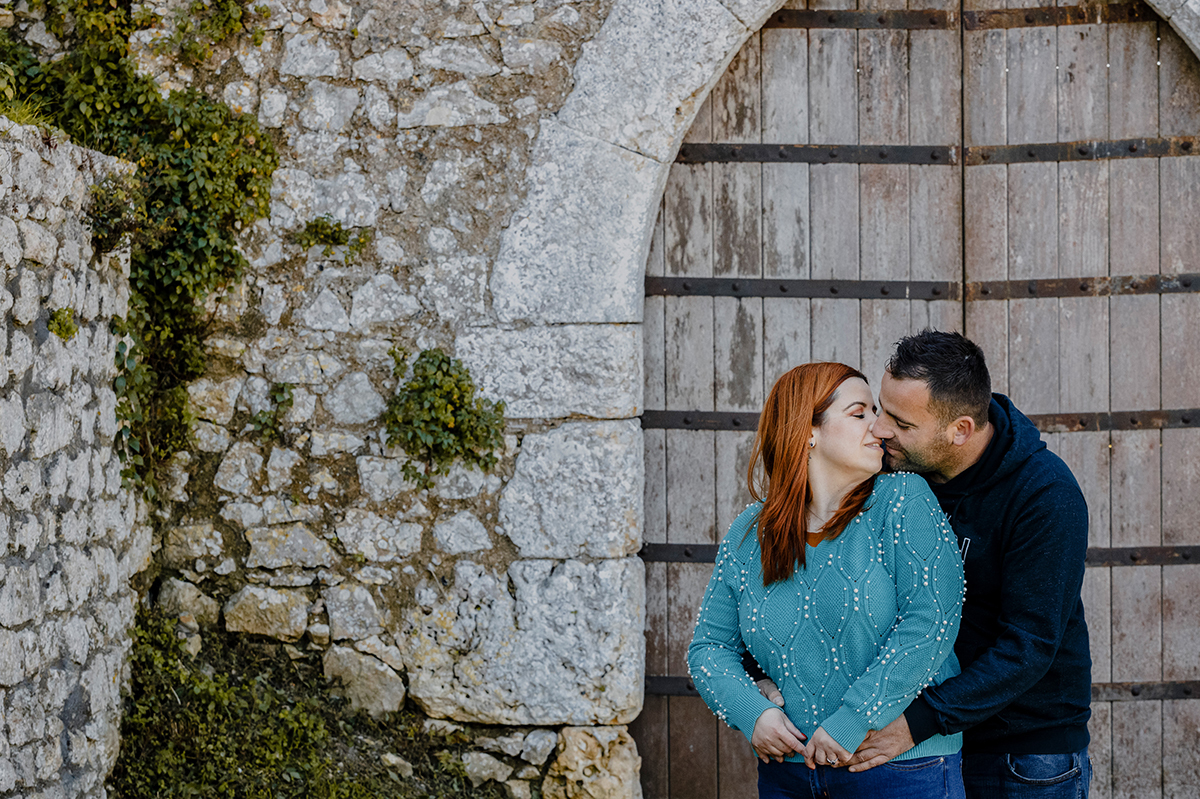 Junto à parede coberta de trepadeiras, Mónica vira-se para Ricardo e os dois beijam-se com a leveza de quem se escolhe todos os dias. A pedra antiga abraça a intimidade partilhada.