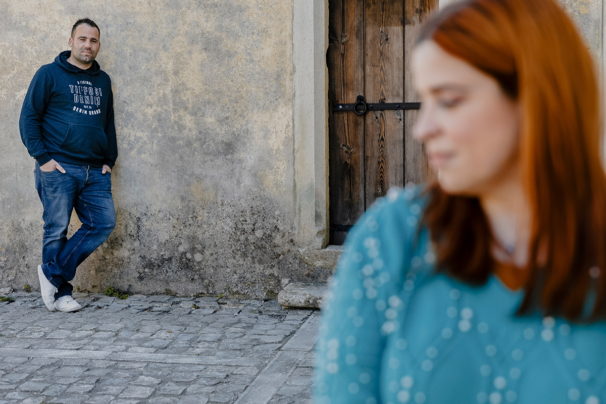 Na foto seguinte, os papéis invertem-se. Ricardo agora está em foco, de olhar firme e mãos nos bolsos, enquanto Mónica, desfocada, observa com ternura. Um espelho de equilíbrio e reciprocidade.