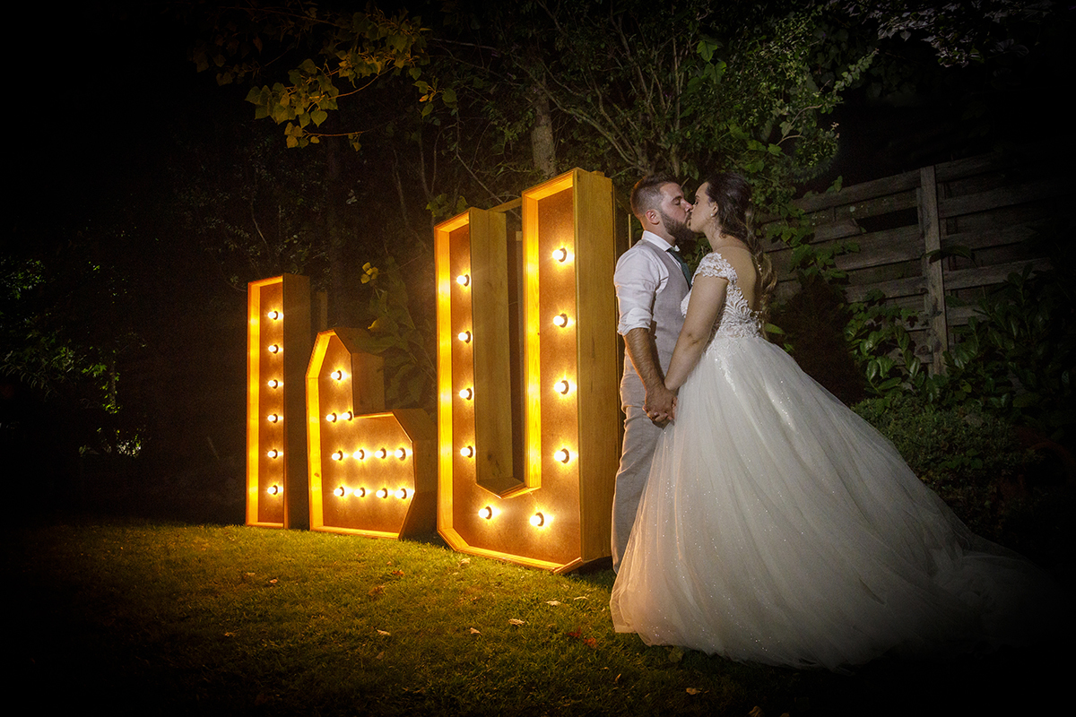Descrição: Aqui ao lado de umas letras grandes : I ❤ U, eles estão frente a frente de mãos dadas a beijarem-se.