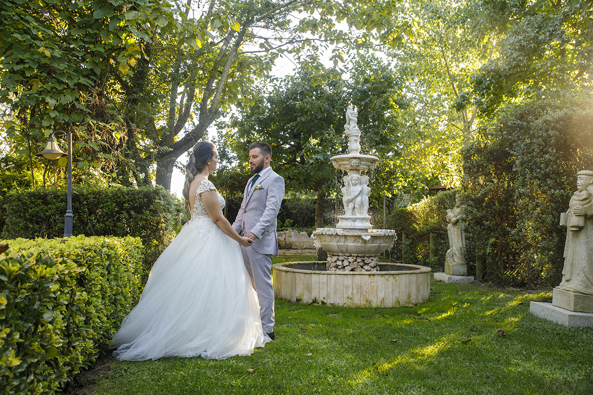 Descrição: Aqui vemos os dois encostados a um muro e planta e os dois frente a frente de mãos dadas a encararem-se felizes e ao seu lado tem uma linda fonte.