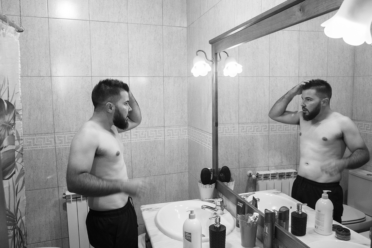 Em tons de preto e branco vemos Ricardo de tronco nu com as mãos no cabelo, concentrado e calmo, num momento íntimo e cru onde começa a preparar-se para o grande dia.