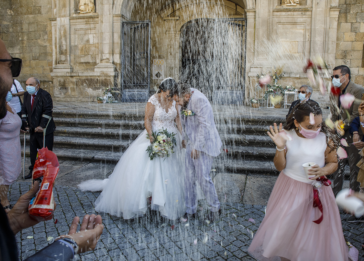 No mesmo instante mágico, captado com o arroz desfocado a cair como se fosse neve de festa, os noivos avançam juntos com um brilho especial na fotografia que parece parada no tempo.