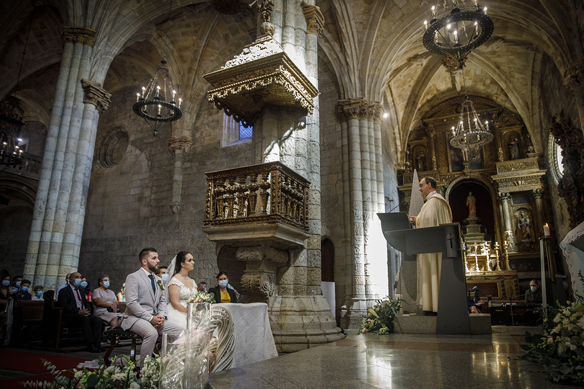 Agora ao pé do altar, vemos Marta e Ricardo sentados lado a lado nas suas cadeiras, atentos ao padre à sua frente, partilhando um silêncio cúmplice e respeitoso no coração da cerimónia.