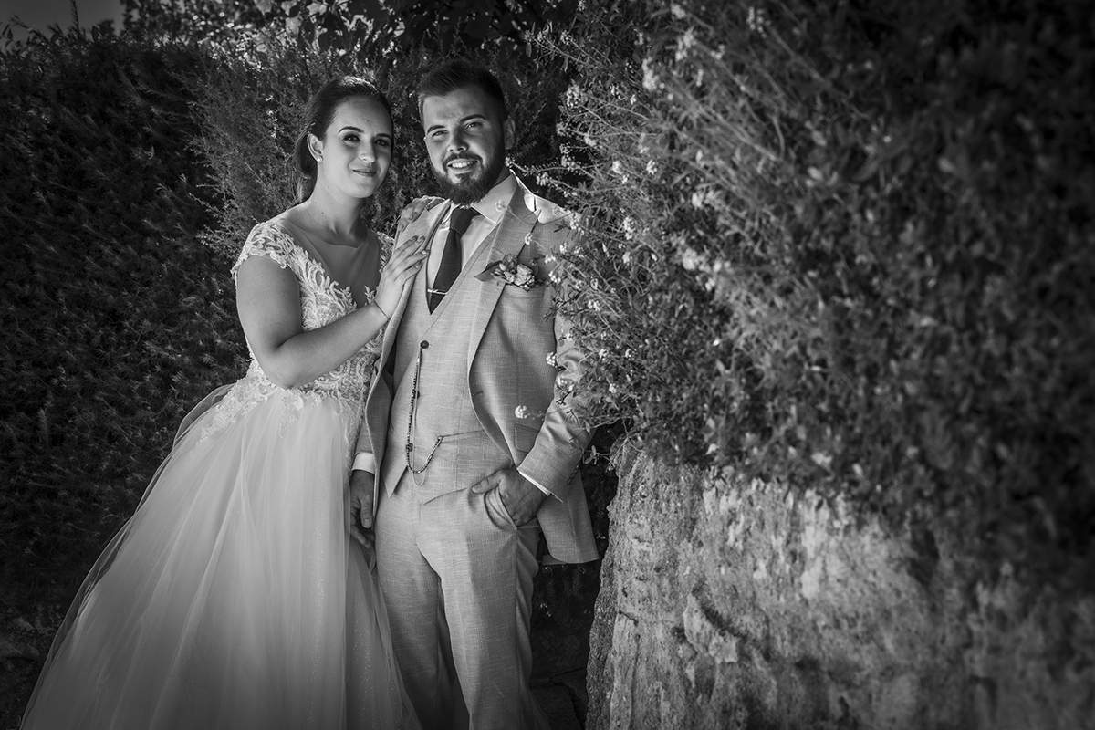 Descrição: Aqui a preto e branco vemos os dois do lado esquerdo da foto e os dois estão lado a lado e ela coloca a sua mão no peito de Ricardo e os dois olham para a câmara felizes com sorrisos.