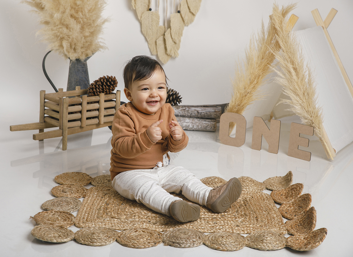 Num cenário encantador digno de uma revista de decoração, o pequeno Daniel está no centro do tapete de corda, rodeado por elementos rústicos e elegantes. As letras “ONE” anunciam o seu primeiro aninho enquanto ele observa tudo com aquele olhar curioso.