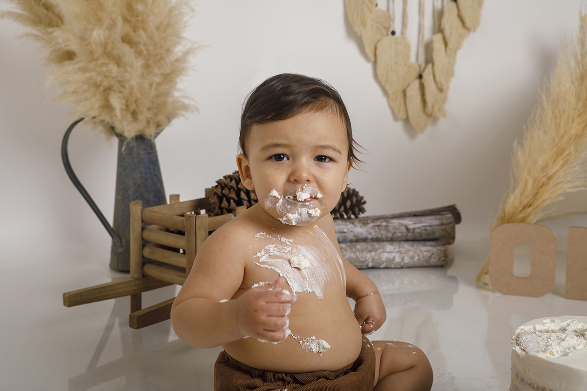 Da cintura para cima, um olhar sério mas encantador. A boca e a barriga decoradas com chantilly comprovam que o bolo foi mesmo saboreado com entusiasmo.