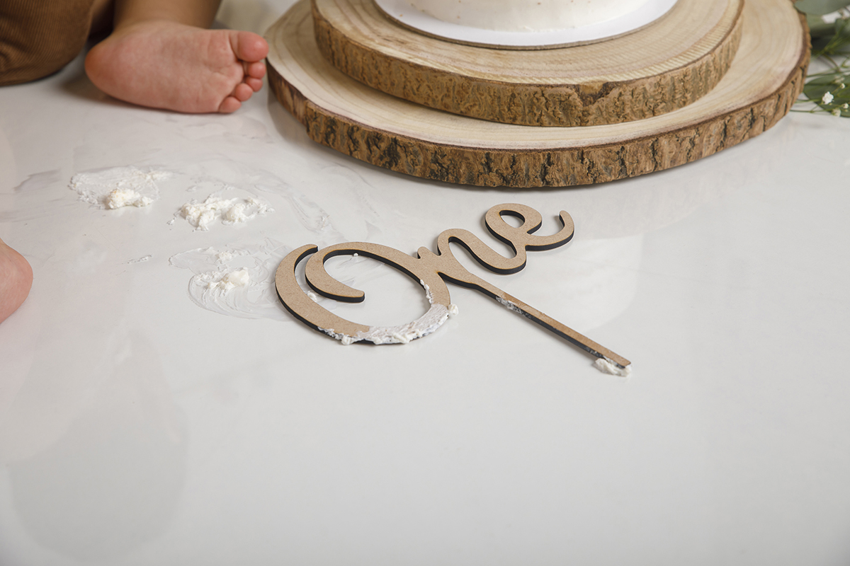 Um plano de detalhe mostra os pezinhos do Daniel entre bolo e plaquinhas no chão. Um caos delicioso e digno de registo.