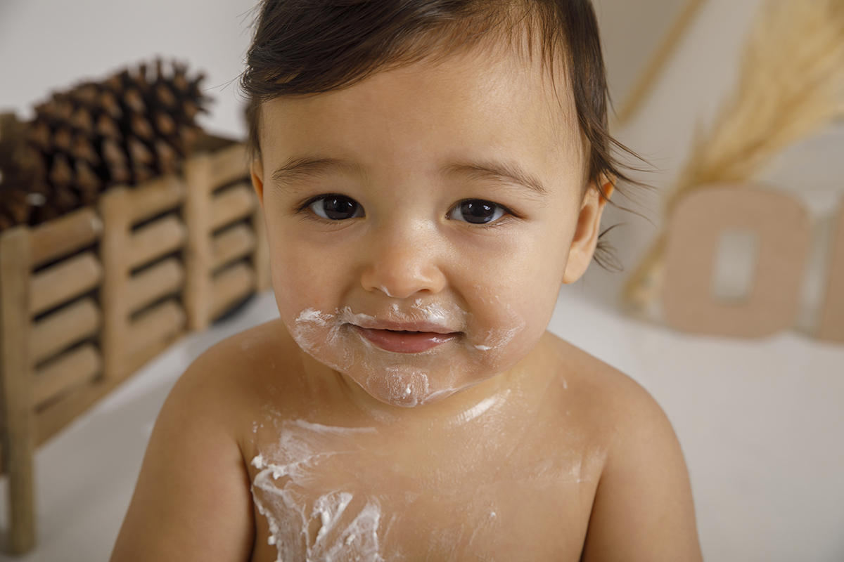 Um plano mais aproximado mostra o nosso príncipe cheio de bolo na cara e no corpo. Ele sorri ligeiramente, como quem se diverte mesmo a fazer a maior bagunça do ano.