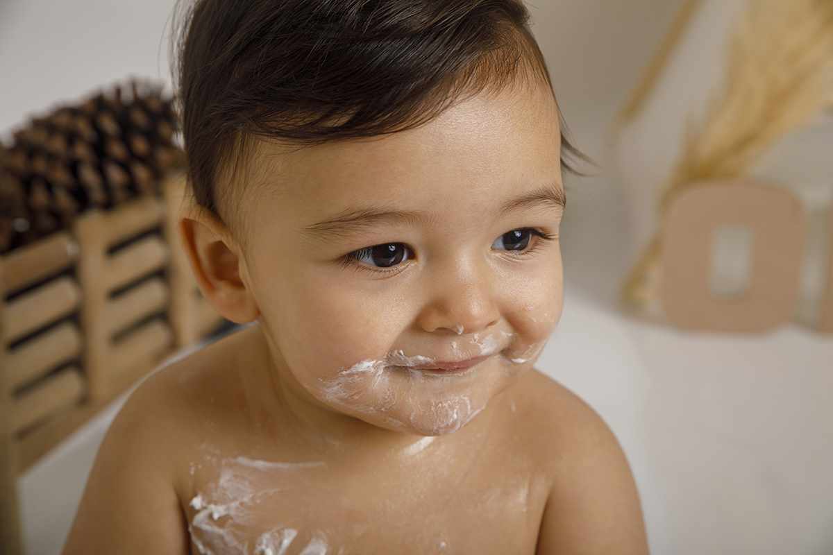 Um close mágico: Daniel sorri ligeiramente para o lado, com a carinha e corpo ainda marcados pela doce batalha com o bolo. Um verdadeiro vencedor.