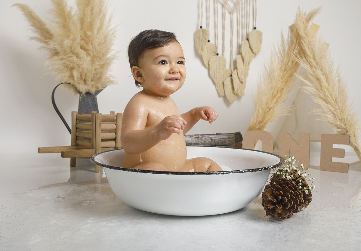 De lado, na bacia, Daniel sorri levemente para cima com mãos ao peito. A felicidade em forma de bebé.