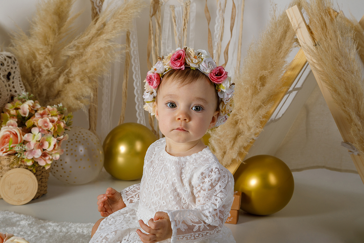 A pequena Constança está com um olhar sério e concentrado, sentada no cenário encantador, com as mãozinhas juntas em pose de yoga, uma verdadeira mini mestre da serenidade!