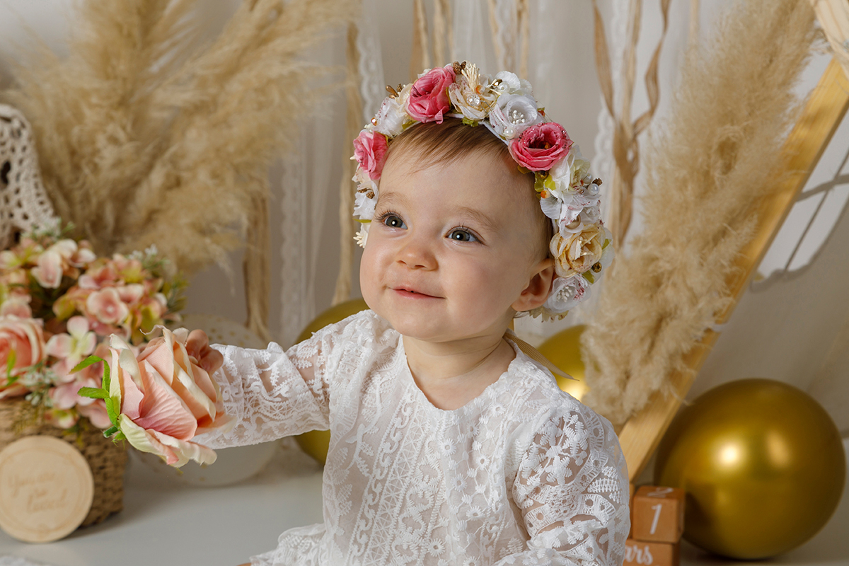 Um olhar de surpresa e encantamento surge no rosto da bebé ao descobrir algo novo do cenário, capturando a essência da infância.