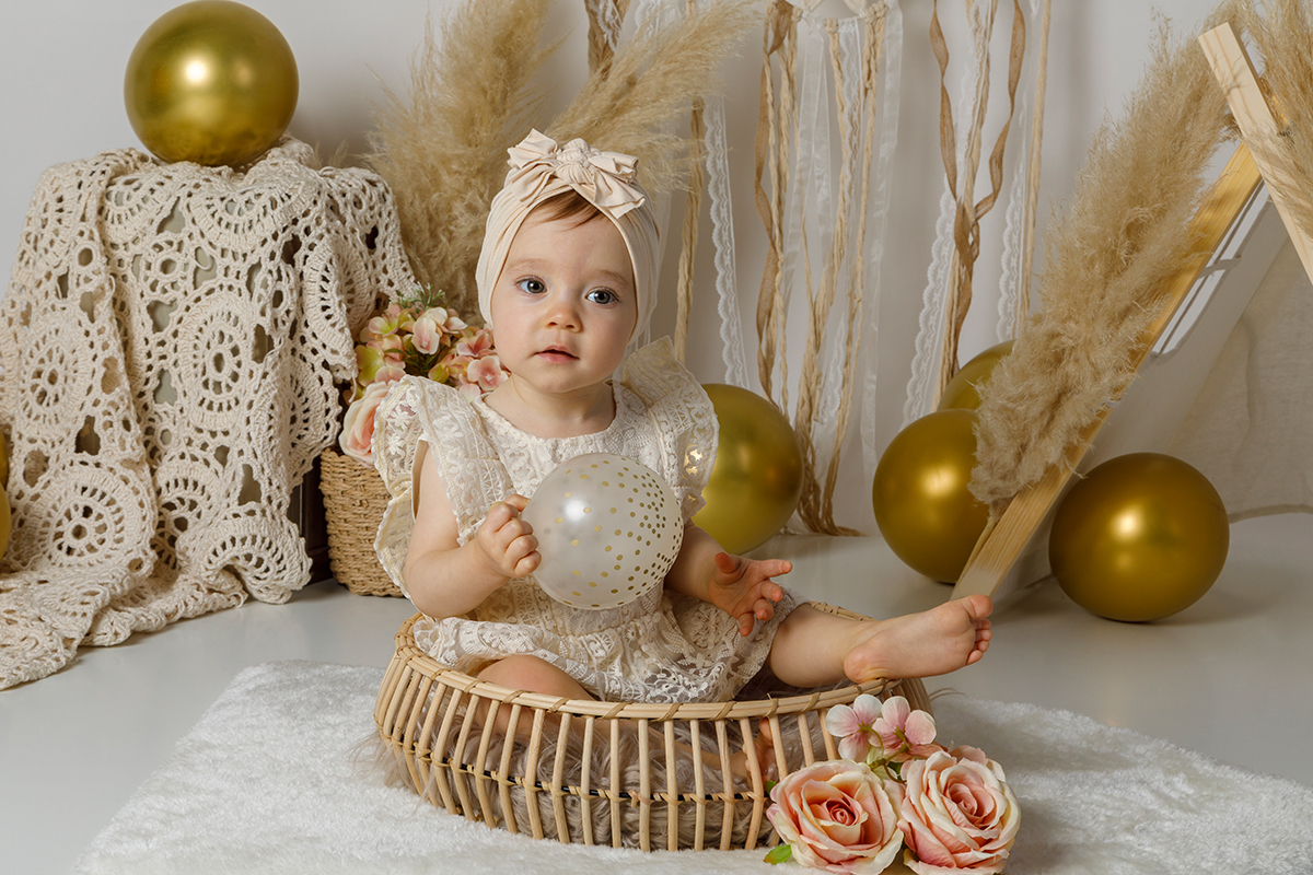 Sentada dentro de um cesto de madeira, com o pé de fora e um balão transparente com brilhos nas mãos, Constança parece uma personagem saída de um conto de fadas em versão moderna.