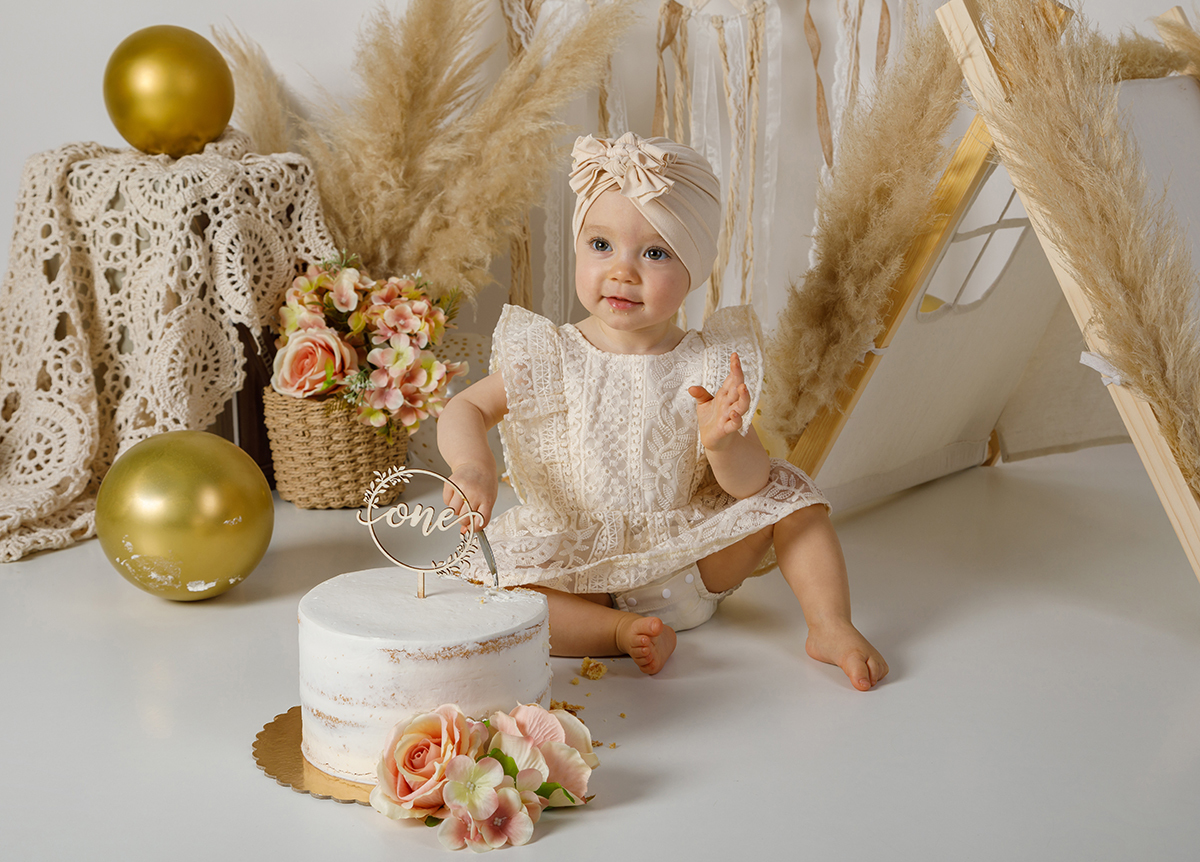 Sentada atrás do bolo, de olhar sereno e feliz, uma mão erguida no ar e a outra perto da colher, como quem celebra o sabor da infância.