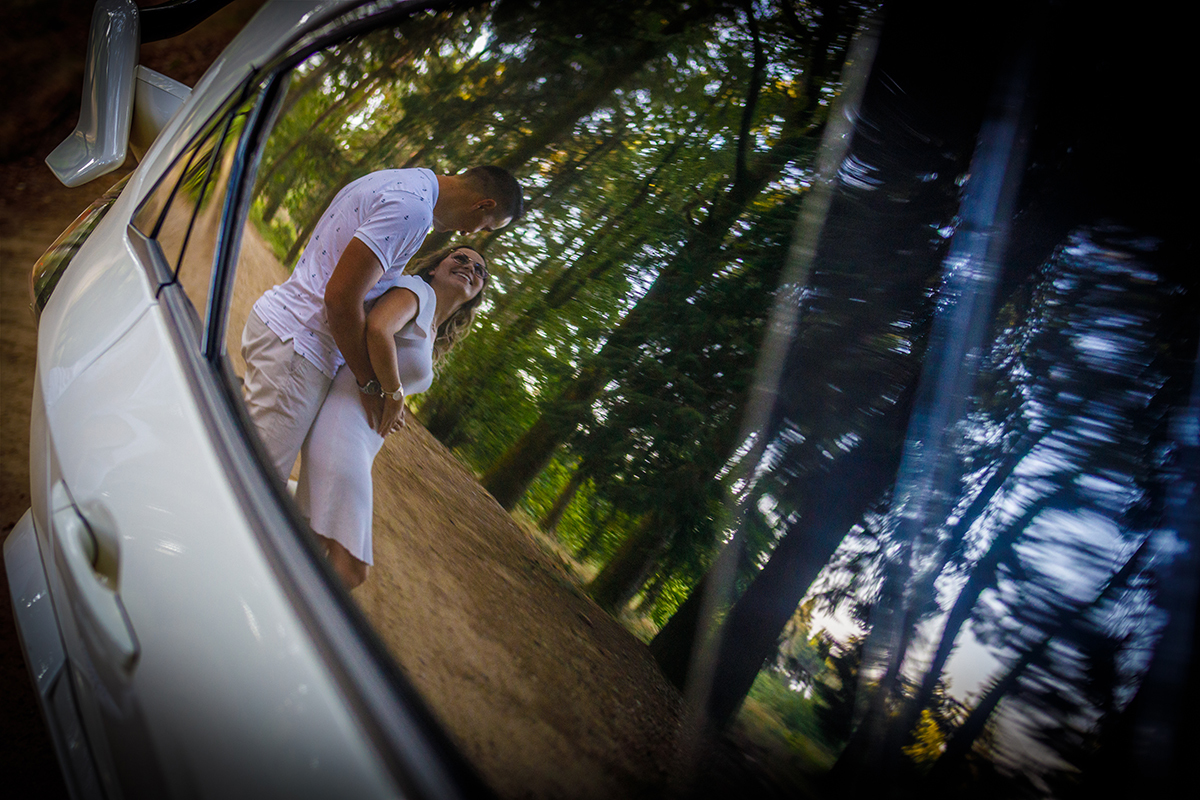 Numa fotografia com vinheta e plano aproximado, vemos o reflexo no vidro da porta do carro. Jorge está atrás com as mãos na barriga de Sabrina, e Sabrina segura-lhe as mãos. Ambos se olham com doçura, num momento captado com sensibilidade.