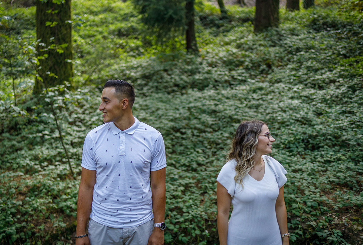 Da cintura para cima, os dois surgem virados para a frente, mas com os rostos voltados para lados opostos. Ambos sorriem com leveza, com um fundo verde possivelmente de trepadeiras. Ricardo Coimbra Fotografo