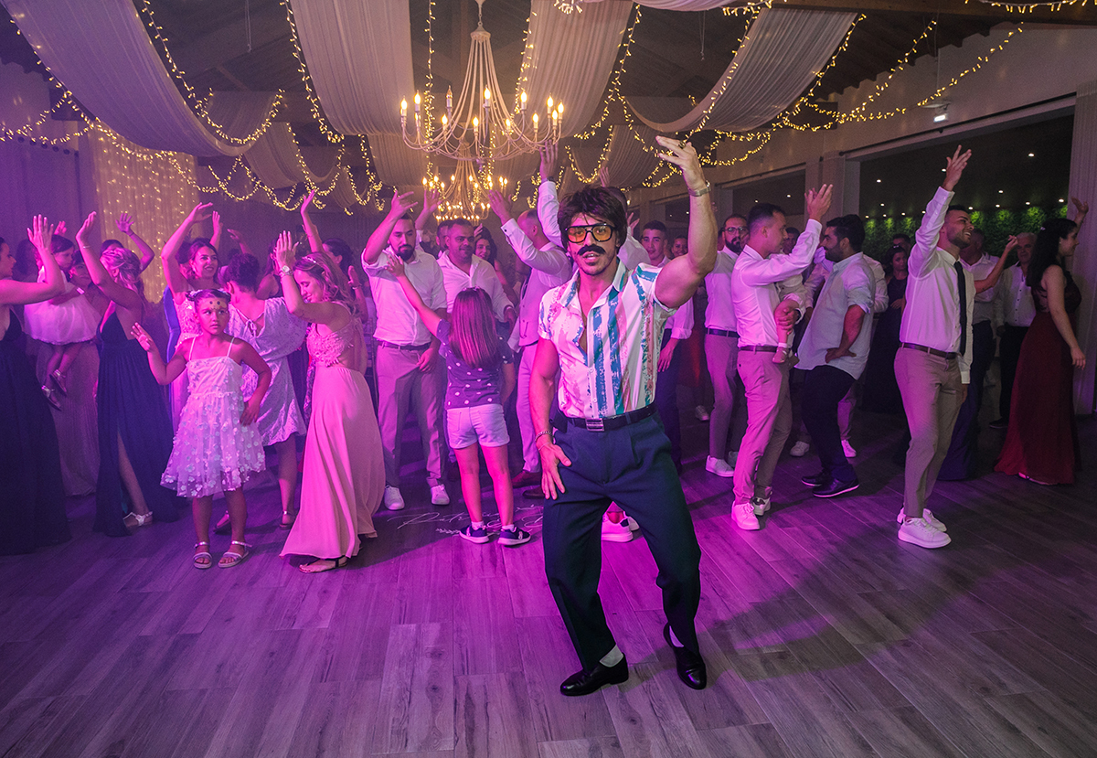 No centro, o Sr. Camaleão dança, braços ao alto, atrás dele, todos se entregam à festa como se o mundo não existisse além dali.