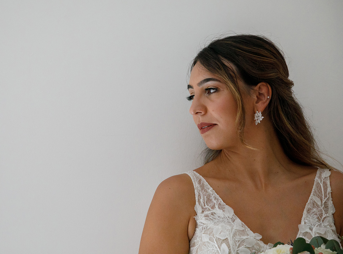 Encostada a uma parede branca, de perfil, Patrícia exibe a sua delicadeza e beleza intemporal, com brincos que reluzem como estrelas junto ao rosto.