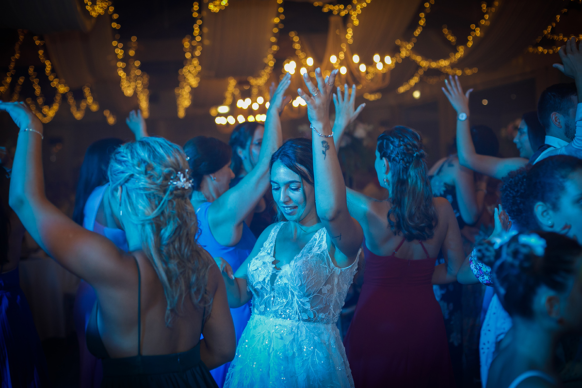 Com luz azul a cobrir o ambiente, vemos todos a dançar. No centro destaca-se a noiva, com as mãos no ar, a aproveitar a festa com um grande sorriso.