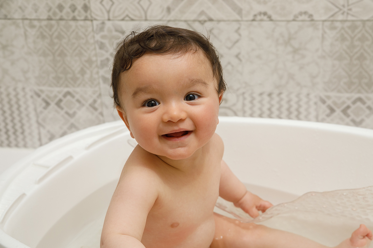 Sentado dentro da bacia, Francisco olha sorridente para a câmara. A água ao seu redor e o olhar brilhante eternizam o encanto do rito sagrado.