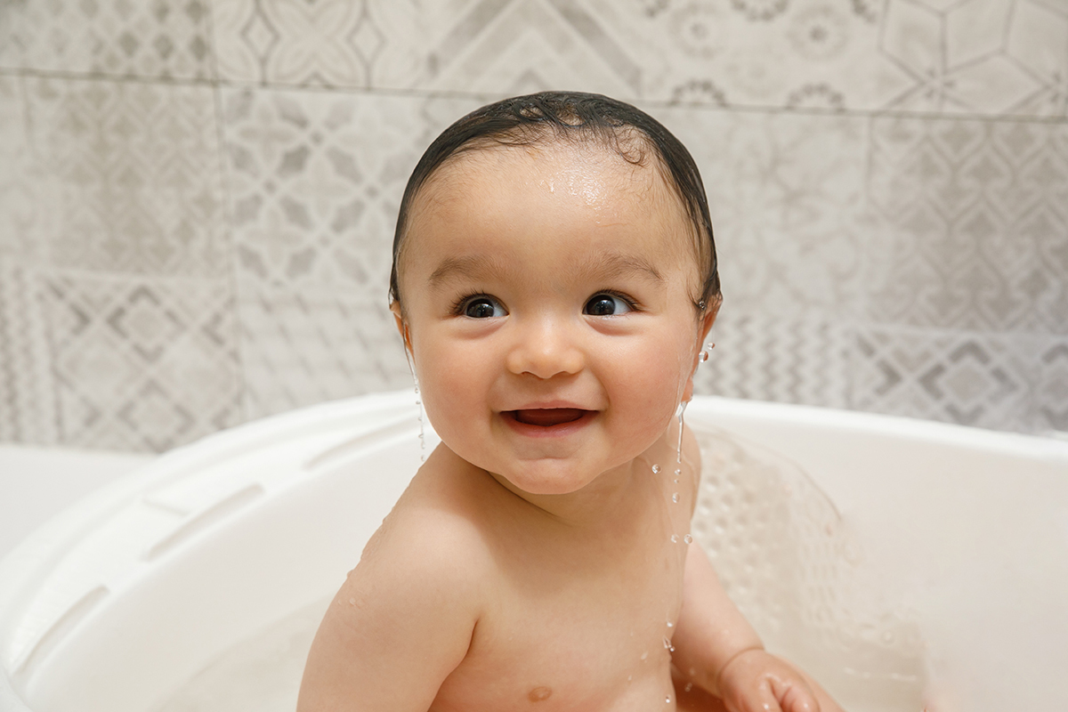 Com o cabelo molhado e gotas a escorrer pelo corpo, Francisco continua dentro da bacia. O sorriso permanece, agora com um brilho novo.