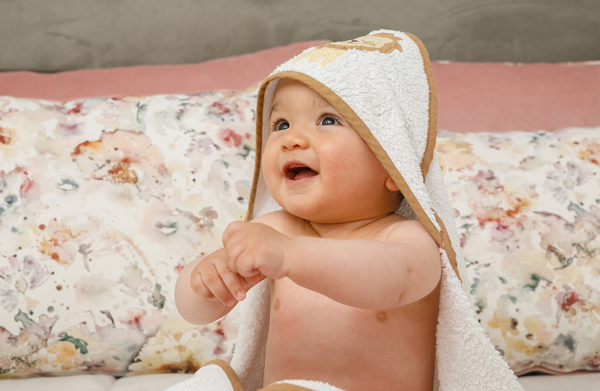 Com a toalha na cabeça como um pequeno robe, Francisco sorri com vontade. As mãos unem-se à frente do pescoço, num gesto terno, e os olhos brilham de alegria. O príncipe do dia vive o seu momento mágico.