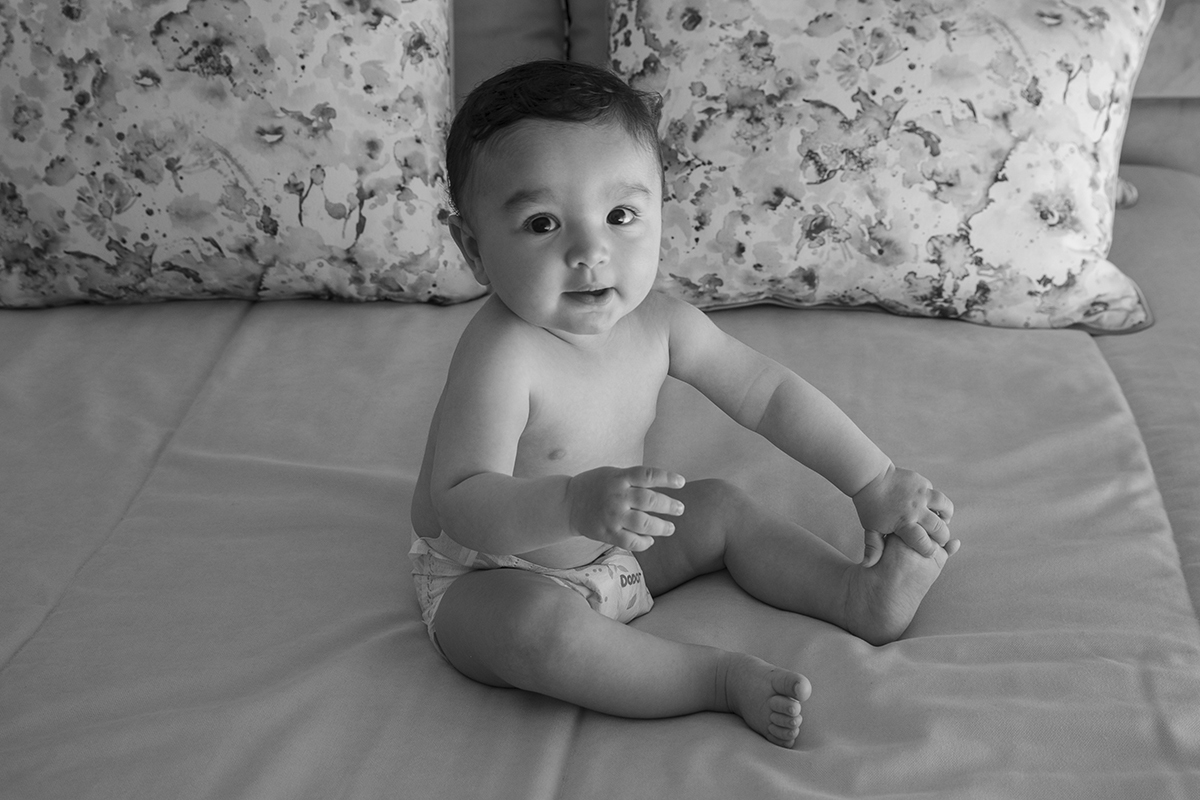 A preto e branco, Francisco surge sentado na cama com uma mão erguida e outra sobre o pé. O olhar sério encontra a lente, num gesto de quem já compreende a importância do dia.