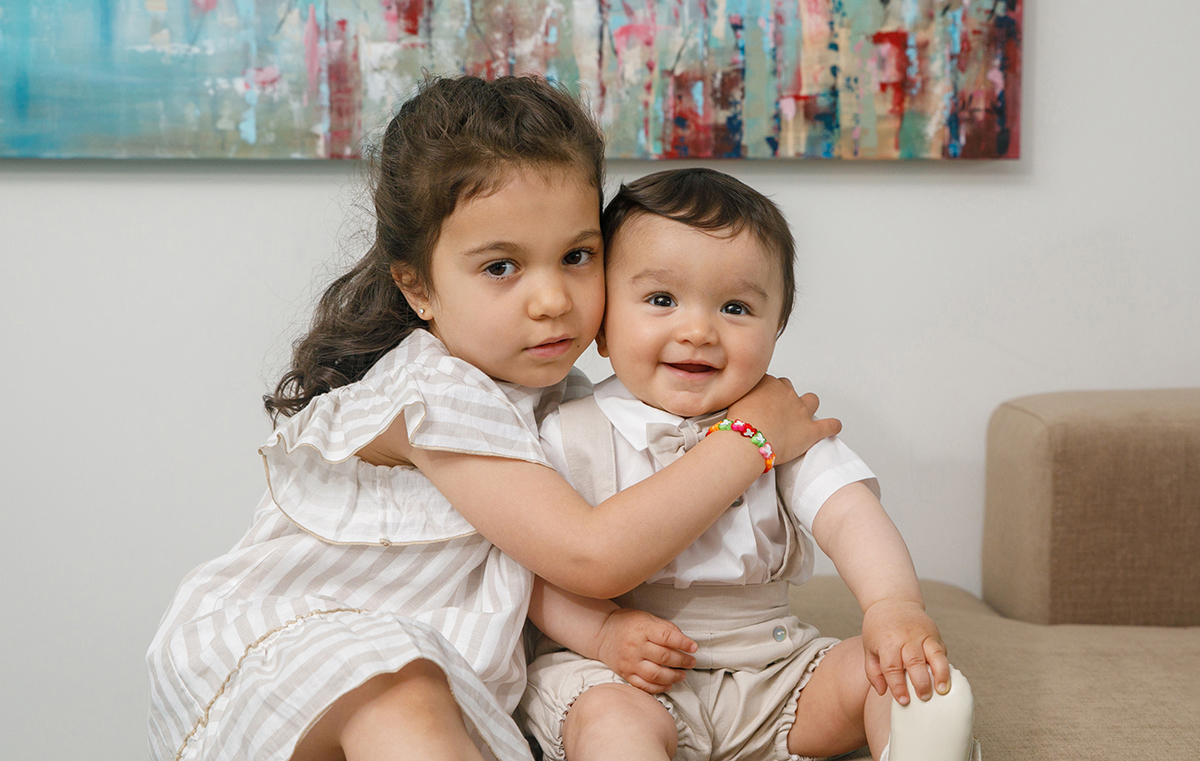 Francisco está sentado ao lado de uma menina que lhe abraça o ombro. Ambos sorriem para a câmara, lado a lado, partilhando um gesto simples e belo de amizade.