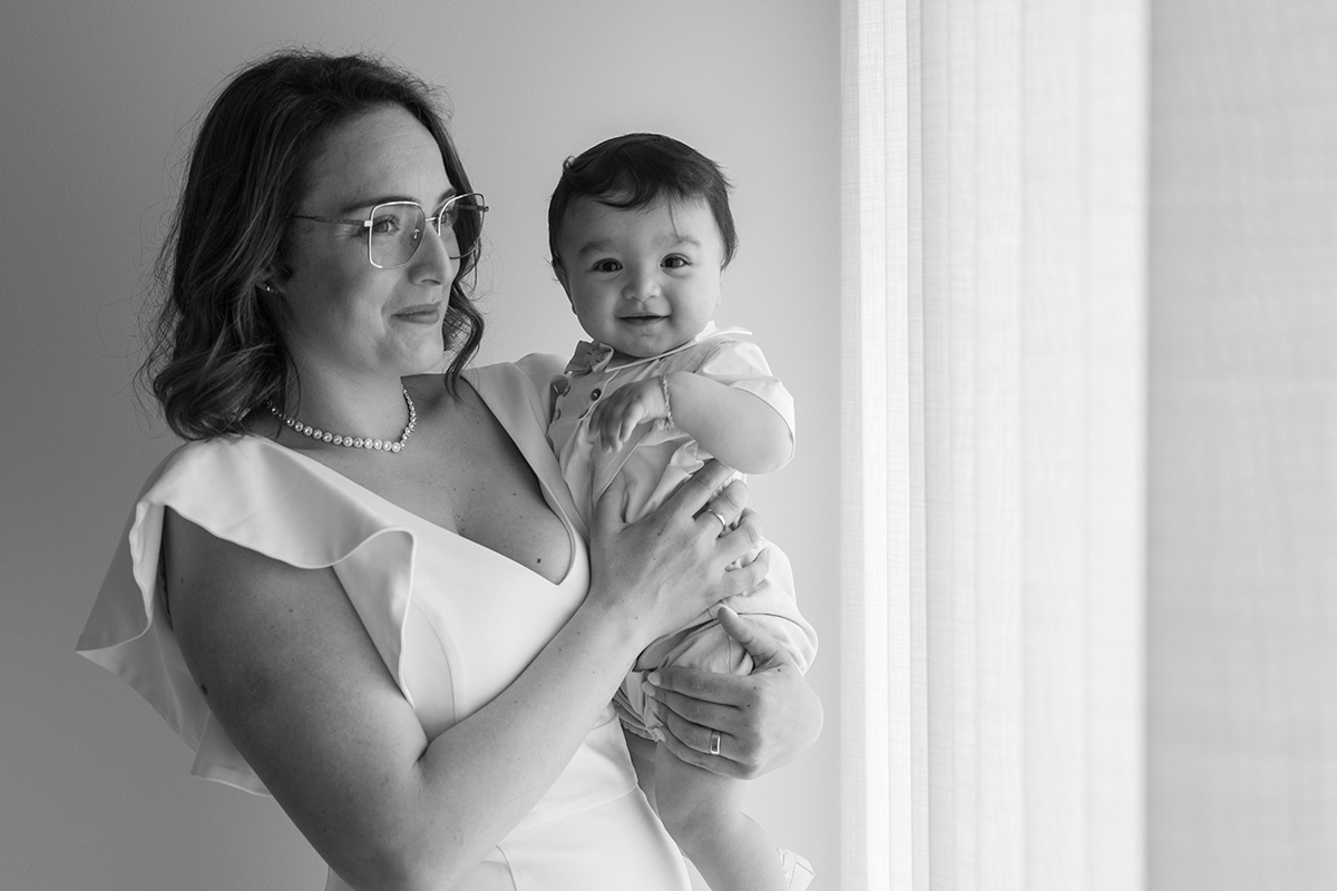 Ainda em preto e branco, a mãe agora olha para a janela, num momento de reflexão suave. Francisco, ao colo, continua a sorrir para a câmara. Dois olhares, duas expressões, um mesmo laço.