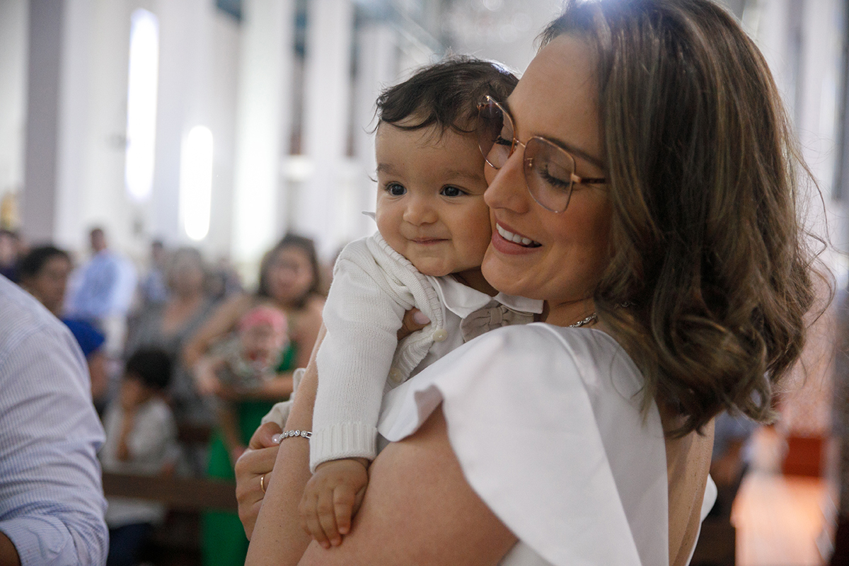 Na igreja, com fundo desfocado, a mãe segura Francisco com ternura. As suas caras tocam-se suavemente num abraço de alma, olhos fechados num instante só deles.