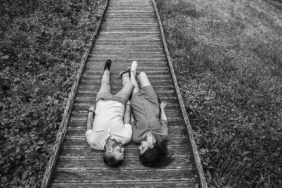 Agora a preto e branco, deitados lado a lado nos passadiços, com as cabeças juntas e os pés apontados para cima, tocam-se levemente nas pernas. Uma imagem serena que transmite intimidade e tranquilidade.