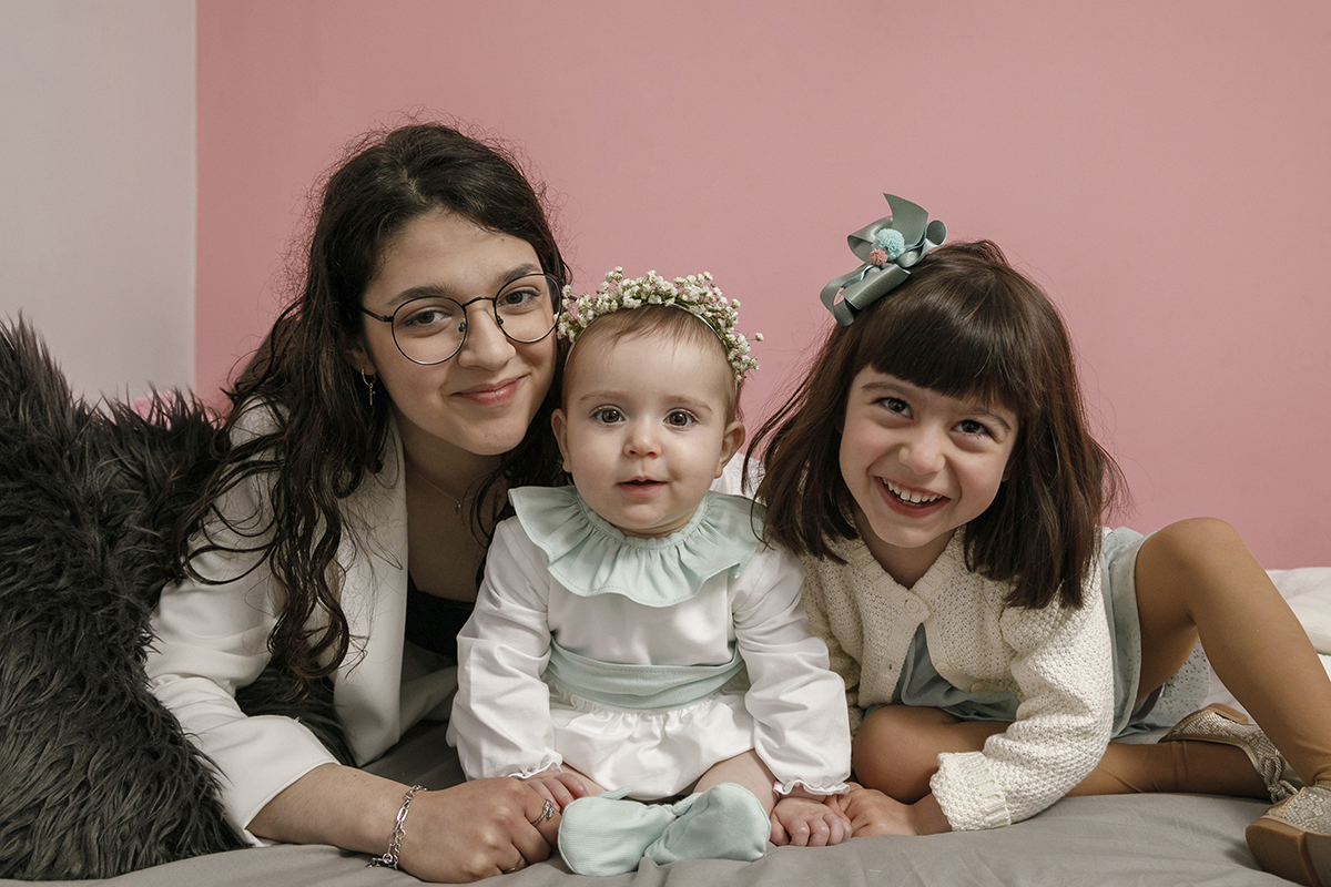 As meninas inclinam-se até à altura de Valentina. A mais velha pousa a mão junto à perna dela, a mais nova aproxima a sua mão da mão de Valentina. Um trio de ternura em perfeita sintonia.