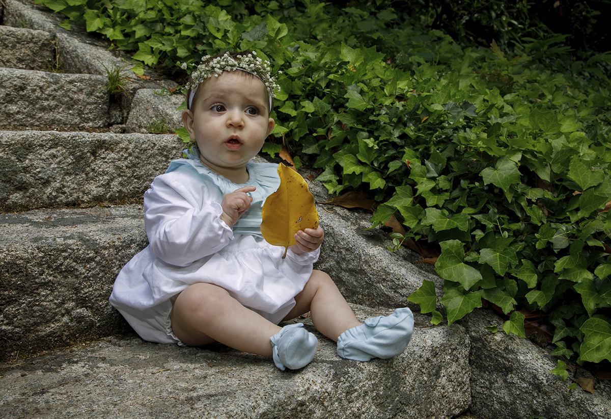 Sentada numa escada de pedra, com trepadeiras a cair ao lado, Valentina observa uma folha amarela. O olhar sério e contemplativo faz do momento uma pintura viva de outono e inocência.