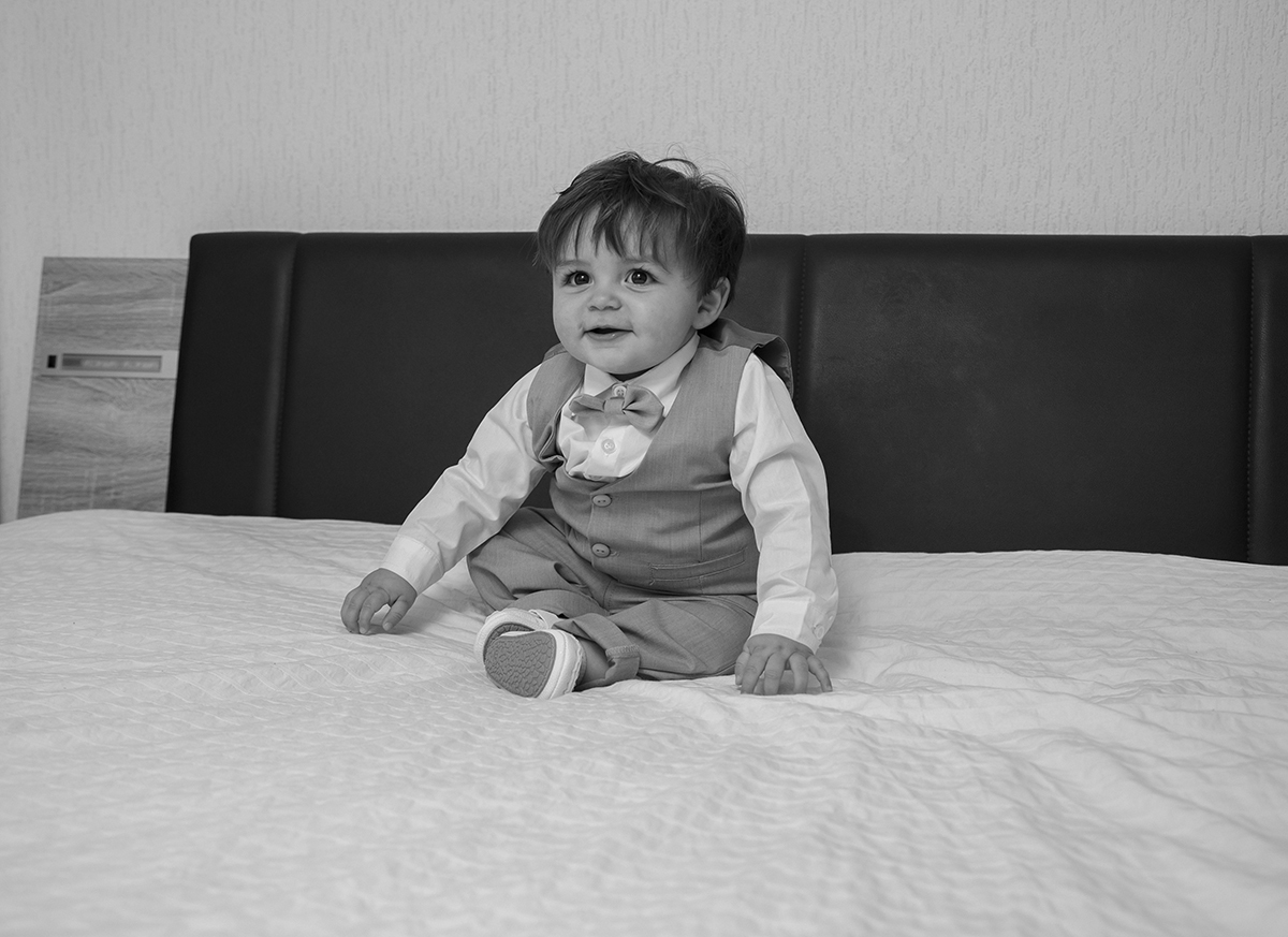 A preto e branco, Gabriel surge vestido e radiante, sentado na sua cama, sorridente, como se sentisse a solenidade do dia.