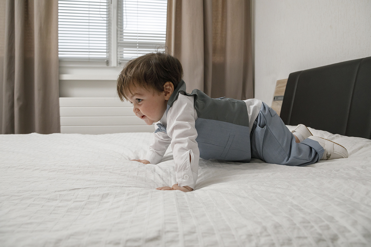 Agora, num ângulo lateral, ele parece fazer flexões, com os olhinhos curiosos e um sorriso travesso. A luz da janela envolve a cena como um abraço suave.